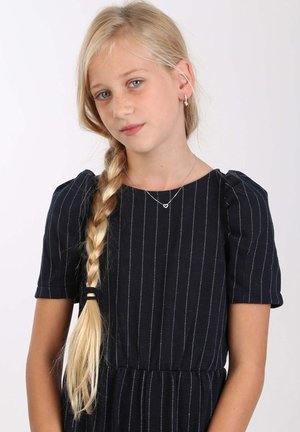 Marineblaues Kleid mit weißen vertikalen Streifen, kurzen Puffärmeln und tailliertem Schnitt. Das Model trägt eine filigrane Herzkettenhalskette und Ohrringe.