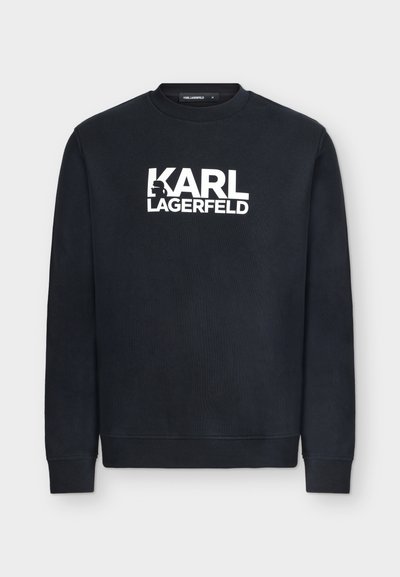 Черна дълга блуза с бял надпис "KARL LAGERFELD" в центъра на гърдите и малка силуетна фигура на Карл Лагерфелд, интегрирана в текста.