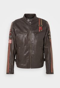 Veste de motard en cuir marron foncé avec fermeture éclair à l'avant, plusieurs patchs et des rayures rouges et beiges sur les manches et la poitrine.