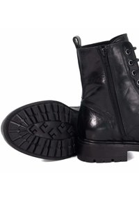 Black leather ankle boots with a side zipper, round toe, and textured rubber sole featuring a grooved pattern for traction.