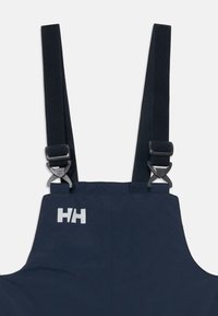 Mörkblå hängslen med justerbara svarta remmar, metallspännen och en vit "HH" logotyp på den övre vänstra sidan.