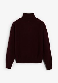 Jersey de cuello alto burdeos hecho de tela suave, con mangas largas, un ajuste relajado y puños y cuello acanalados.
