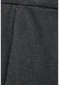Tissu en laine gris foncé avec une texture subtile et des coutures apparentes, probablement une partie d’un pantalon formel ou d’une veste de costume.