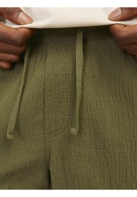 Olijfgroene, gestructureerde broek met een elastische tailleband met trekkoord, met subtiele lijnen en een zachte, gekreukte stof.