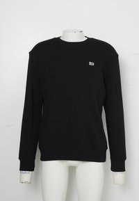 Zwarte sweater met lange mouwen en ronde hals, met een klein wit "Lee"-logo op de linkerborst, tentoongesteld op een wit mannequin torso.
