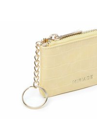 Pochette en cuir jaune au motif crocodile avec des finitions dorées, dotée d'une fermeture éclair et d'une chaîne reliée à un porte-clés circulaire.