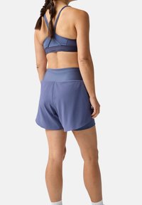 Sport-BH und Shorts-Set aus hellblauem Stoff; die Shorts haben einen breiten Bund und eine lockere Passform mit einem subtilen Glanz und einer glatten Textur.