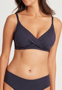 Marineblauwe bikini-top met een wikkelontwerp, verstelbare banden en een gladde stof. Beschikt over een klassieke vorm en subtiele textuur.