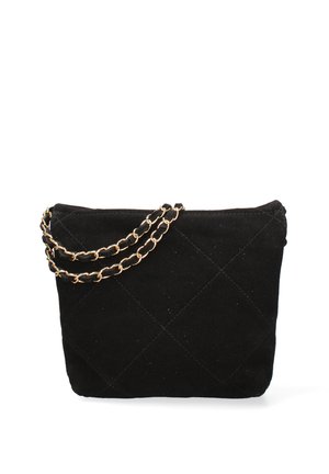 Sac à main en daim matelassé noir avec une bandoulière chaîne noire et dorée reposant sur un fond blanc.