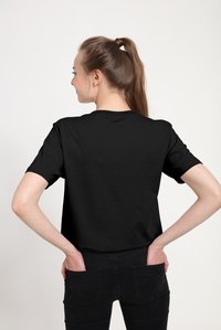 Sort T-shirt lavet af blødt stof, korte ærmer, rund halsudskæring og løs pasform. Ingen synlige logoer eller mønstre på bagsiden.