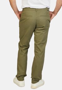 Olijfgroene katoenmix broek met een rechte pijp, achterzakken en een zachte textuur, gecombineerd met witte sneakers.