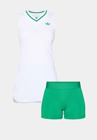 Weißes ärmelloses Shirt mit grünem V-Ausschnitt und Logo, kombiniert mit grünen, figurbetonten Shorts. Der Stoff ist glatt und elastisch, geeignet für aktive Bekleidung.