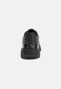 Black athletic sneaker shown from the rear with thick sole, curved heel detail, and padded collar against white background.