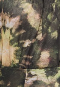 Tissu tie-dye présentant un motif abstrait dans des tons terreux de vert, marron et rose doux, avec une apparence texturée et légère.