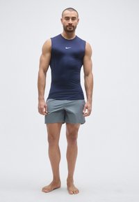 Top atletico smanicato blu navy con logo bianco, abbinato a pantaloncini grigio chiaro. Realizzato in tessuto liscio e leggero per il massimo comfort.