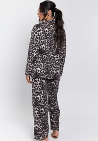 Conjunto de pijama de estampado de leopardo en tejido suave, que incluye una camiseta de manga larga y pantalones sueltos, con cintura elástica y corte relajado.