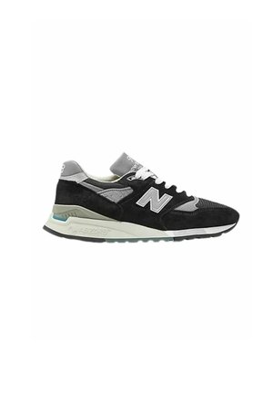 Sneaker in suede e mesh nera con un accento grigio sul tallone, logo bianco e una suola in gomma grigia chiara con dettagli turchesi.