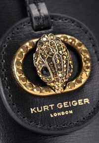Cuir noir avec une boucle décorative en ton doré présentant un design texturé et des cristaux enchâssés. Comprend le marquage "Kurt Geiger London".