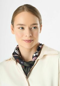 Seidenschal mit floralem Muster in gedämpften Tönen von Schwarz, Pink und Grün. Der Schal ist am Hals verknotet und zeigt seine glatte Textur.