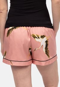 Roze satijnen shorts met zwarte piping, voorzien van een kraanpatroon in wit en zwart, met een gatherede tailleband, een ontspannen pasvorm en een knie-lange snit.