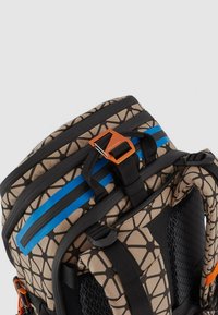 Zaino con motivo geometrico beige e nero, dettagli blu, spallacci regolabili e pannello nero testurizzato. Realizzato in tessuto resistente.