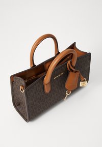 Sac à main monogram marron avec des poignées en cuir lisse beige, quincaillerie dorée et un porte-clés détachable. Dispose d'une fermeture zippée et d'une forme structurée.