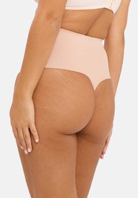 Panty gainant nude taille haute avec une texture lisse et un design sans coutures, présentant une découpe arrondie à l'arrière et une couverture moyenne.