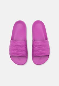 Lila halkskor med texturerade remmar och öppen tå-design. Tillverkade av flexibelt material, med tre framträdande horisontella ribbor.