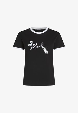 Zwarte t-shirt met korte mouwen en witte kraag, met een grafisch ontwerp van twee katten in een zonnebril en "Karl" in cursieve tekst. Geschilderde afwerking.