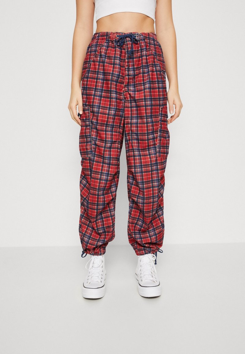 Pantalons cargo à carreaux rouges et marine avec une coupe décontractée, une taille élastique et des poignets ajustables ; disposent de poches latérales et d'un cordon de serrage.