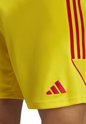 Gelbe Sportshorts mit roten Akzenten und drei roten Streifen an der Seite. Enthält ein rot gesticktes Adidas-Logo am unteren Saum.