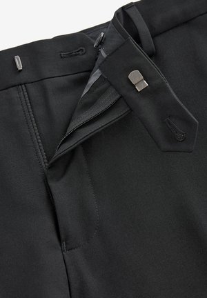 Pantaloni neri con fronte piatto, dotati di zip e chiusura con gancio, e una cucitura dettagliata. Il tessuto è liscio con una finitura opaca.