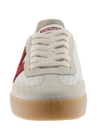Witte sneaker met beige suède details, een rode ster aan de zijkant, dikke witte veters en een zool van gumrubber, gezien van voren.