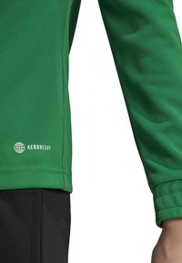 Groene langemouwen sportshirt van textuurstof. Bevat een Aeroready-logo in het wit aan de onderzijde links. Gladde naden en een aansluitend ontwerp.