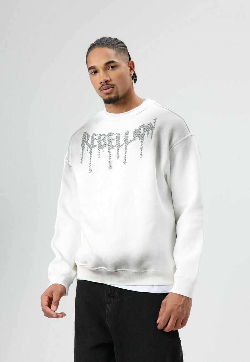 Witte sweatshirt met ‘REBELLION’ in druipende zilveren letters. Heeft een losse pasvorm, geribbelde manchetten en zoom. Soepele textuur.
