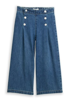 Szerokie spodnie dżinsowe w kolorze niebieskim o wysokim stanie, z dwoma pionowymi rzędami po trzy białe guziki z przodu.