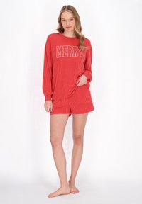 Rød ribbet pyjamas sæt med en langærmet skjorte med "MERRY" i hvid skrift og matchende shorts. Blødt stof, afslappet pasform.