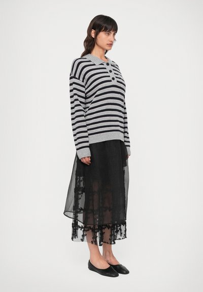 Hall mustar ja navy triibuline kootud kampsun, millel on kraega kaelus, kombineeritud musta läbipaistva seeliku ning lillede detailidega alläärega.