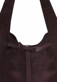 Bruine suède totebag met een gladde textuur, voorzien van een platte band, een strikaccent en een minimalistisch open bovenkant ontwerp.