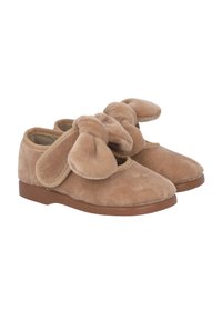 Zapatillas de felpa beige con una forma suave y redondeada. Presentan grandes lazos de tela en la parte delantera y una suela plana de goma marrón para mayor comodidad.