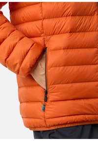 Oranje pufferjack met een ritszak en een zichtbare zwarte rits. Gequiltte textuur met een klein blauw en geel vlagaccent.