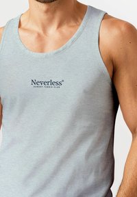 Light grey cotton tank top featuring a round neckline and the text "Neverless SUNDAY TENNIS CLUB" in dark blue lettering at the center.