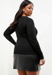 Zwarte gebreide trui met lange mouwen, slim-fit ontwerp en ronde halslijn. Gecombineerd met een zwarte leren minirok, met een gladde textuur en een strakke Silhouet.