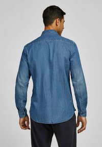 Jeanshemd mit langen Ärmeln, einem hellen bis dunklen blauen Farbverlauf, klassischem Kragen und geknöpften Manschetten. Gerundeter Saum und strukturierten Stoff.