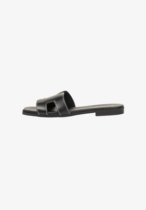 Chanclas negras con suela plana, que presentan un diseño troquelado y costuras blancas contrastantes. Fabricadas en material sintético.