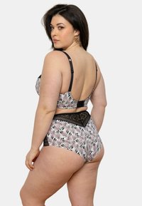 Ensemble soutien-gorge et culotte taille haute avec des motifs floraux noirs sur fond blanc, des accents en dentelle noire et des bretelles réglables.