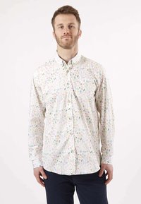 Chemise à manches longues à boutons en tissu léger blanc avec un motif floral coloré, dotée d'un col standard et d'un ourlet arrondi.