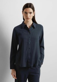 Dark navy button-up shirt with long sleeves, a classic collar, smooth texture, and a curved hem; features front button closure.