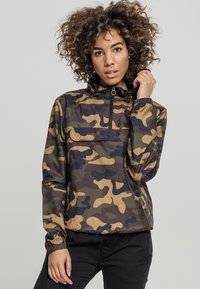 Camouflage pullover jacket with zip collar, elastic cuffs, and a pocket; features brown, green, and black patterns on a shiny fabric.