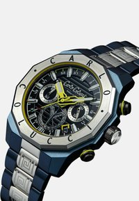 Schwarz und silberne achteckige Uhr mit einem strukturierten Armband, gelben Akzenten, mehreren Zifferblättern und einer großen Krone zum Einstellen der Zeit.